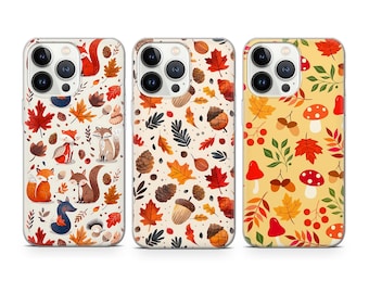 May include: Three iPhone cases featuring a autumnal design. The cases have a white background with a pattern of orange, red, brown, and yellow leaves, acorns, mushrooms, and foxes.