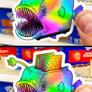May include: A holographic sticker of a anglerfish with a toaster on its head. The toaster has two slices of toast with sprinkles inside. The sticker has the text "Ryan McCrips" on the bottom right corner.
