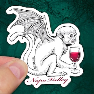May include: A black and white illustration of a monkey with wings holding a glass of red wine. The monkey is sitting on a white background with the text "Napa Valley" below it.