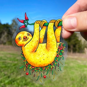 May include: A yellow sloth hanging upside down with a green branch and red peppers. The sloth is surrounded by a green, yellow, and brown border that looks like a taco.