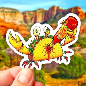 May include: A cartoon crab holding a taco with a bottle of hot sauce being poured into it. The hot sauce is labeled "Hot Sauce".
