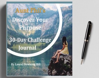May include: A blue and green book cover with a white circle and the text "Aunt Phil's Discover Your Purpose 30-Day Challenge Journal" and "By Laurel Downing Bill". The cover features a photo of a woman sitting on a rock overlooking a lake.