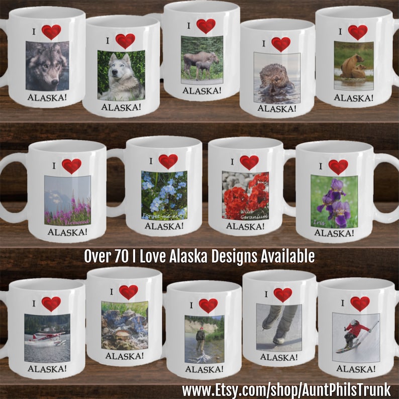 May include: A collection of 10 white ceramic mugs with red hearts and various images of Alaska. The mugs feature images of a wolf, a dog, a moose, an otter, a bear, flowers, a plane, a landscape, a person fishing, ice skates, and a skier. The text "I Love Alaska!" is printed on each mug. Over 70 I Love Alaska Designs Available. www.Etsy.com/shop/AuntPhilsTrunk