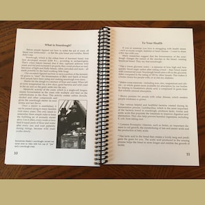 May include: Open book with spiral binding, featuring text about sourdough bread and its health benefits. The pages display information on sourdough's history, preparation, and nutritional advantages. Includes a vintage image of people.