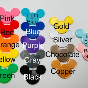 May include: A collection of colorful Mickey Mouse head-shaped cutouts in various colors, including pink, red, orange, yellow, green, light blue, blue, purple, gray, black, gold, silver, chocolate, copper, ice blue, and rose gold. Each cutout has a color name printed on it.