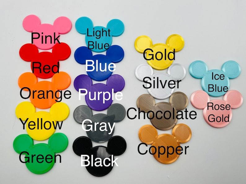 May include: A collection of colorful Mickey Mouse head-shaped cutouts in various colors, including pink, red, orange, yellow, green, light blue, blue, purple, gray, black, gold, silver, chocolate, copper, ice blue, and rose gold. Each cutout has a color name printed on it.
