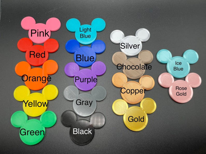 May include: A collection of colorful Mickey Mouse head-shaped items. Colors include pink, red, orange, yellow, green, light blue, blue, purple, gray, black, silver, chocolate, copper, ice blue, and rose gold. Each item has the color name printed on it.