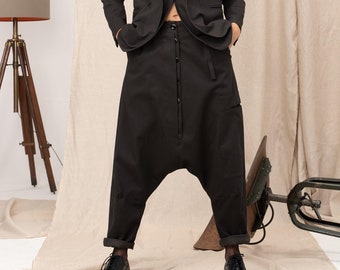 Puede incluir: Una chaqueta negra con cierre de botones y un pantalón negro de diseño único. El pantalón tiene cierre de botones y pierna ancha.