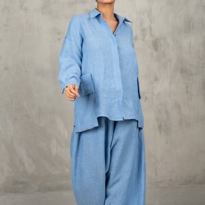 May include: A light blue linen shirt and pants set. The shirt has a button-down collar and long sleeves. The pants are wide-legged and have a relaxed fit.