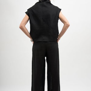 May include: A black linen top with a mock neck and short sleeves, paired with black linen wide-leg pants.