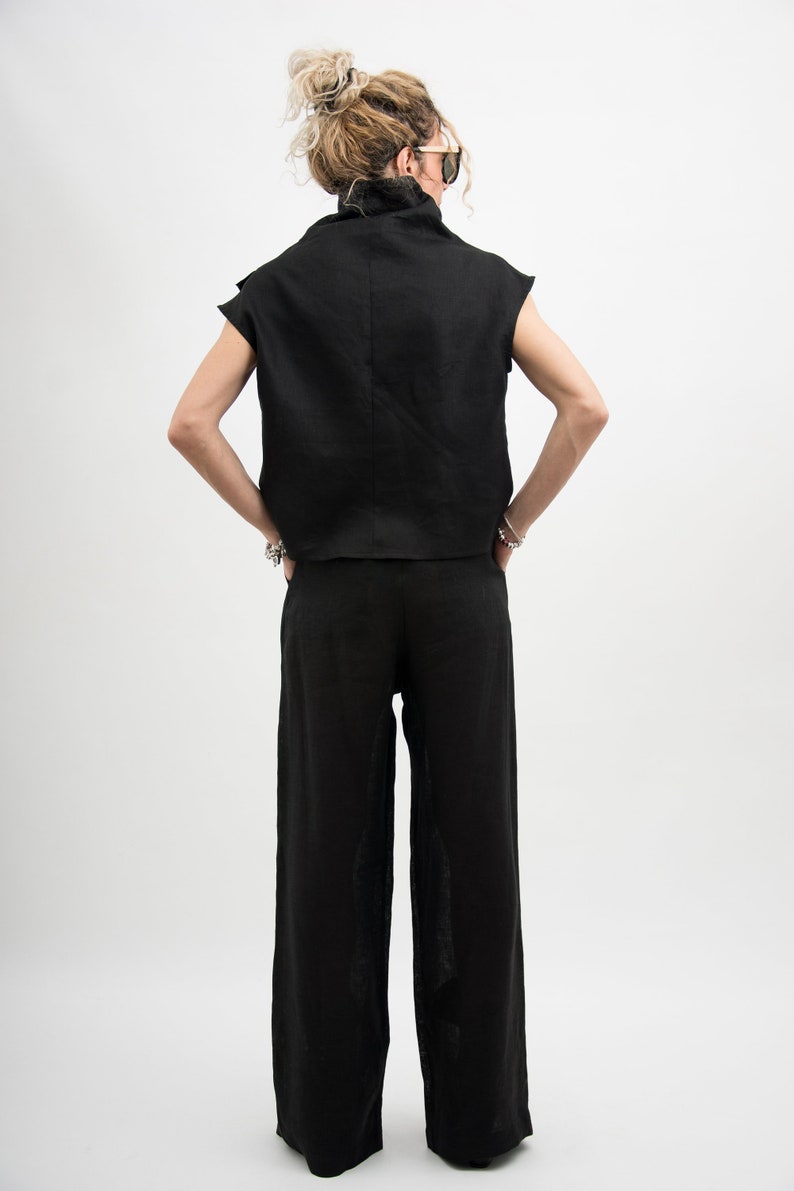 May include: A black linen top with a mock neck and short sleeves, paired with black linen wide-leg pants.