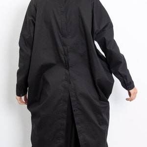 May include: A black long-sleeved shirt with a button-up front and a relaxed fit. The shirt has a collar and a slightly oversized silhouette.