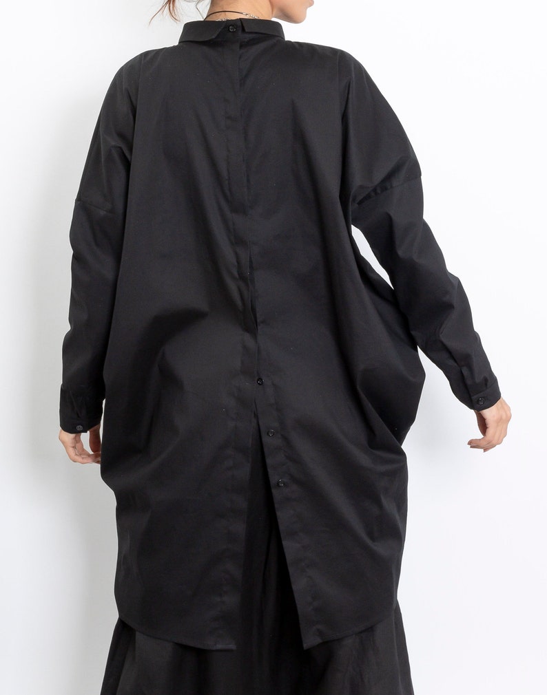 May include: A black long-sleeved shirt with a button-up front and a relaxed fit. The shirt has a collar and a slightly oversized silhouette.