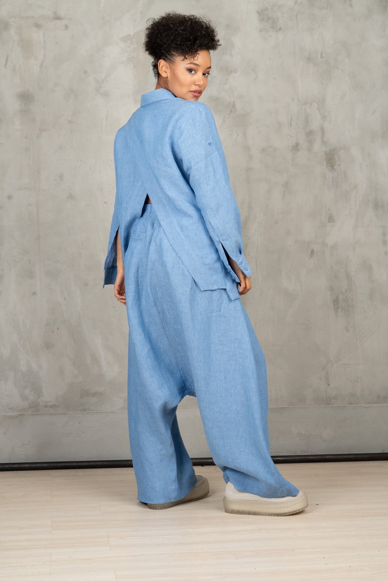 May include: A light blue linen pantsuit with a long-sleeved shirt and wide-leg pants. The shirt has a back cutout and the pants have a loose, flowing fit.