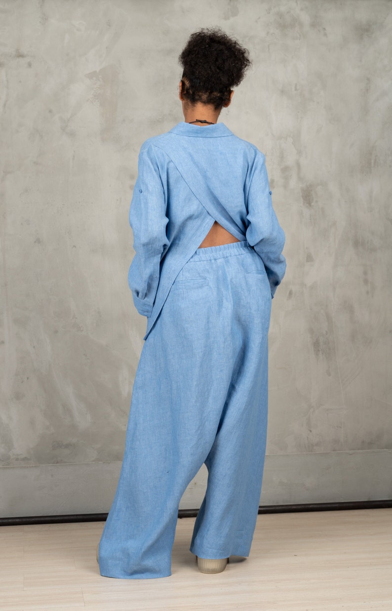 May include: A light blue linen jumpsuit with a criss-cross back detail. The jumpsuit has a relaxed fit and wide legs.