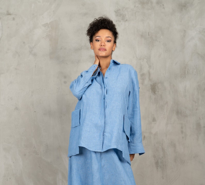 May include: A light blue linen shirt and skirt set. The shirt has a button-up front and long sleeves. The skirt is a-line and falls to the knees.