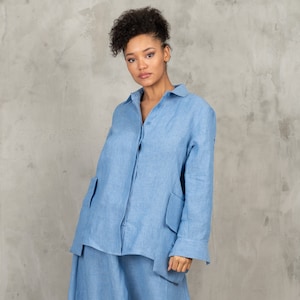 May include: A light blue linen shirt with long sleeves and a button-up front. The shirt has two large patch pockets on the front and a relaxed fit.