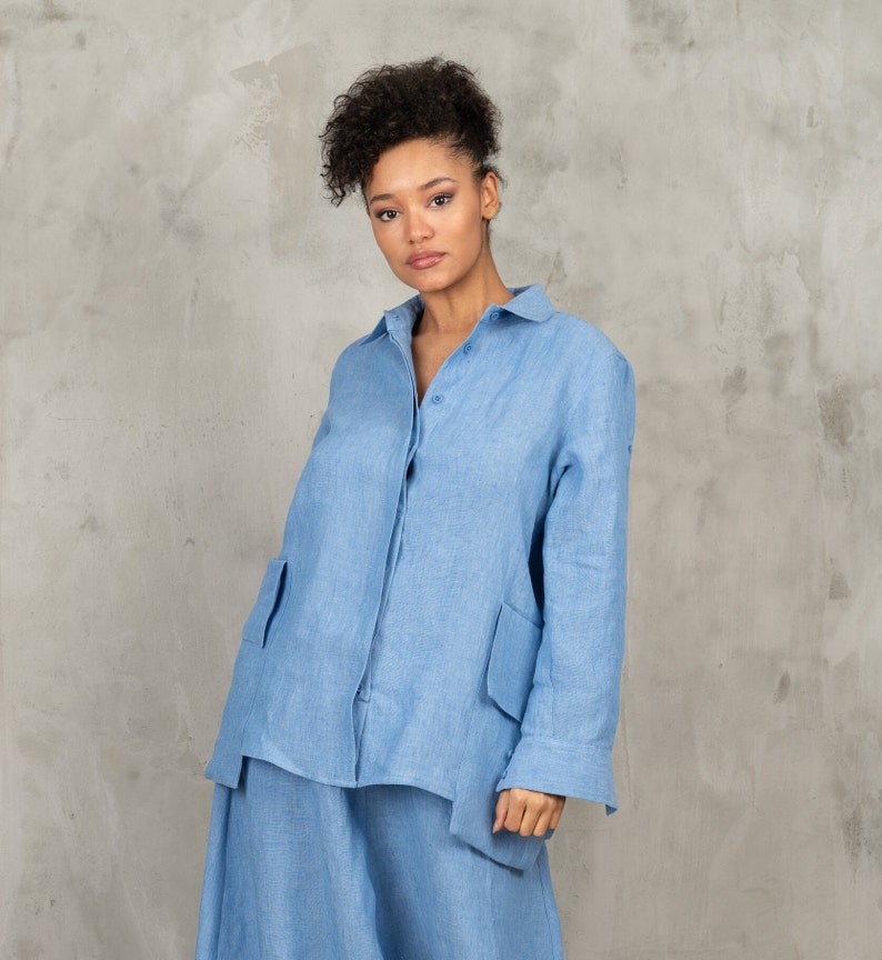 May include: A light blue linen shirt with long sleeves and a button-up front. The shirt has two large patch pockets on the front and a relaxed fit.