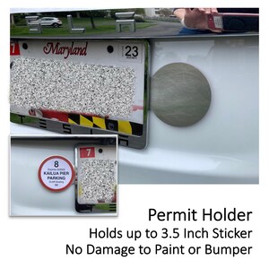 May include: A silver permit holder attached to a white car. The holder is designed to hold a sticker up to 3.5 inches. The image also shows a Maryland license plate and a parking permit sticker.