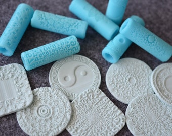 May include: A set of blue plastic rollers with different patterns and a set of white plastic molds with different designs, including a yin yang symbol, numbers, and intricate patterns.