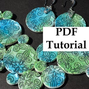 Könnte beinhalten: Ein handgefertigtes Halsketten- und Ohrring-Set mit kreisförmigen Anhängern in Blau- und Grüntönen. Die Anhänger haben eine strukturierte Oberfläche mit einem floralen Design. Das Bild enthält auch den Text "PDF Tutorial".