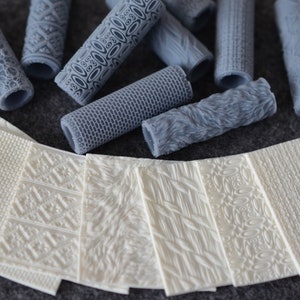 Può includere: Un set di 10 mattarelli in silicone grigi con vari motivi in rilievo, e 10 tappetini in silicone bianchi con motivi in rilievo corrispondenti.