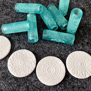 Könnte beinhalten: Ein Set aus sieben türkisfarbenen Nudelholz mit komplizierten Mandala-Mustern. Vier weiße runde Silikonmatten mit dem gleichen Mandala-Muster sind ebenfalls enthalten.