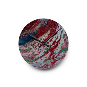 May include: Round wall clock with a vibrant abstract design. The clock face features a swirling pattern of red, blue, green, and white. Black clock hands indicate the time. The clock is a decorative item for any room.