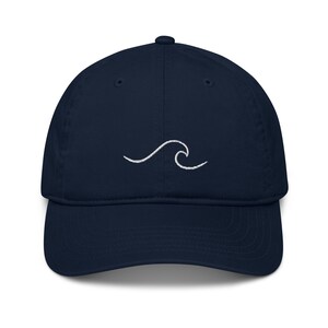 May include: A navy blue baseball cap with a white embroidered wave design.