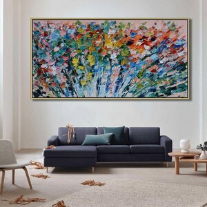 May include: Abstract painting with a colorful, textured, brushstroke style. The painting features a variety of colors, including blue, green, yellow, pink, and red. The painting is framed in a gold frame and is hanging on a white wall.