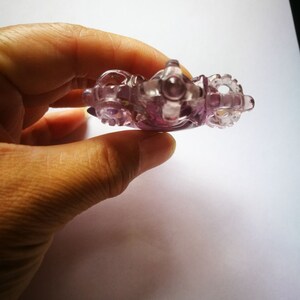 May include: A purple glass figurine of a carriage with intricate details. The carriage has wheels and a detailed design.