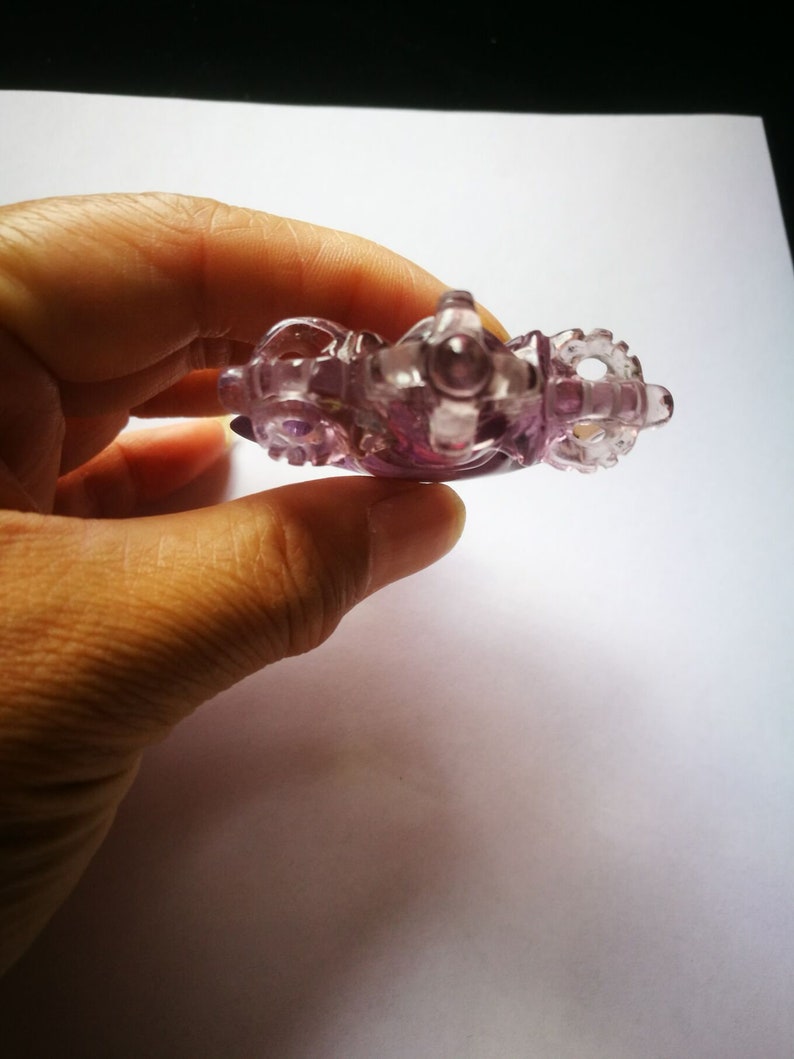 May include: A purple glass figurine of a carriage with intricate details. The carriage has wheels and a detailed design.
