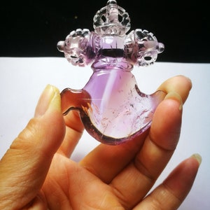 May include: A purple amethyst crystal carved into a traditional Tibetan prayer wheel with a crown on top.