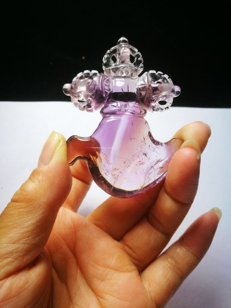 May include: A purple amethyst crystal carved into a traditional Tibetan prayer wheel with a crown on top.