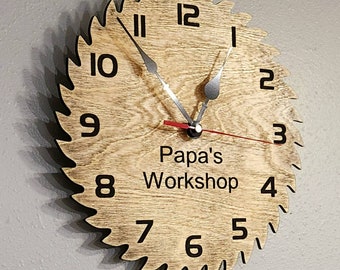 May include: A wooden clock shaped like a saw blade with black numbers and hands. The clock face has the text "Papa's Workshop" in the center.