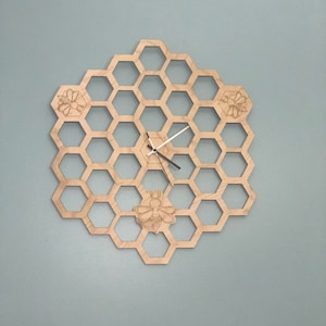 May include: A wooden clock shaped like a honeycomb with three bees carved into the design. The clock has black hands and a white face.