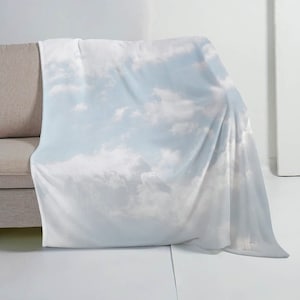 May include: A soft, white fleece throw blanket with a printed design of a blue sky and white clouds.