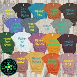 May include: A collection of 20 t-shirts in various heather colors with different color text printed on each shirt. The text on the shirts includes names like Heather Aqua, Heather Autumn, Heather Brown, Heather Columbia Blue, Heather Deep Teal, Heather Dust, Heather Grass Green, Heather Ice Blue, Heather Magenta, Heather Marmalade, Heather Maroon, Heather Mauve, Heather Mustard, Heather Orange, Heather Orchid.
