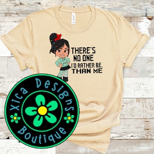 May include: A tan t-shirt with a cartoon character wearing a green shirt and a red bow. The text on the shirt reads "There's no one I'd rather be, than me".