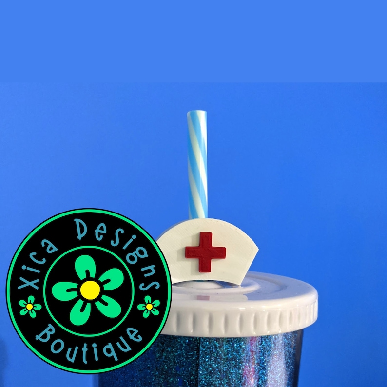 May include: A blue glitter tumbler with a white lid and a white and blue striped straw. The straw has a white nurse's hat topper with a red cross on it. The tumbler has a sticker on the side that says "Xica Designs Boutique".