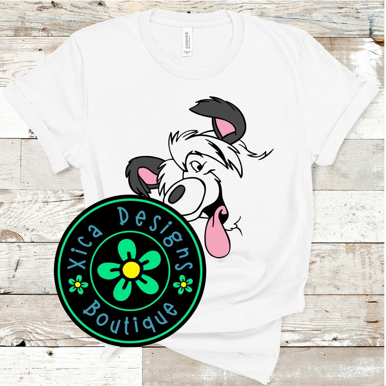 May include: White t-shirt with a cartoon dog peeking out from behind a black circle with a green flower and the text "Xica Designs Boutique".