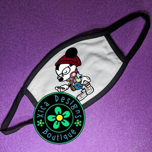 May include: White face mask with a black border. The mask features a cartoon illustration of Mickey Mouse wearing a red beanie, glasses, and headphones. The text "Xica Designs Boutique" is printed in a circle below the illustration.