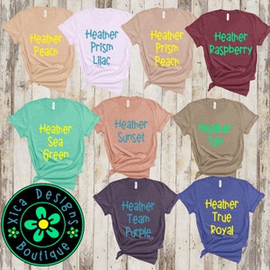 May include: Nine different colored t-shirts with various text printed on them. The text includes "Heather Peach", "Heather Prism Lilac", "Heather Prism Peach", "Heather Raspberry", "Heather Sea Green", "Heather Sunset", "Heather Tan", "Heather Team Purple", and "Heather True Royal".