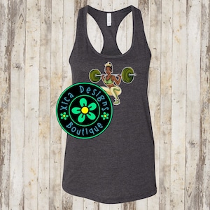 May include: Dark gray racerback tank top featuring a graphic of a woman lifting weights. The woman is wearing a green sports bra and leggings. The tank top has the text "Xica Designs Boutique" in a circular design.