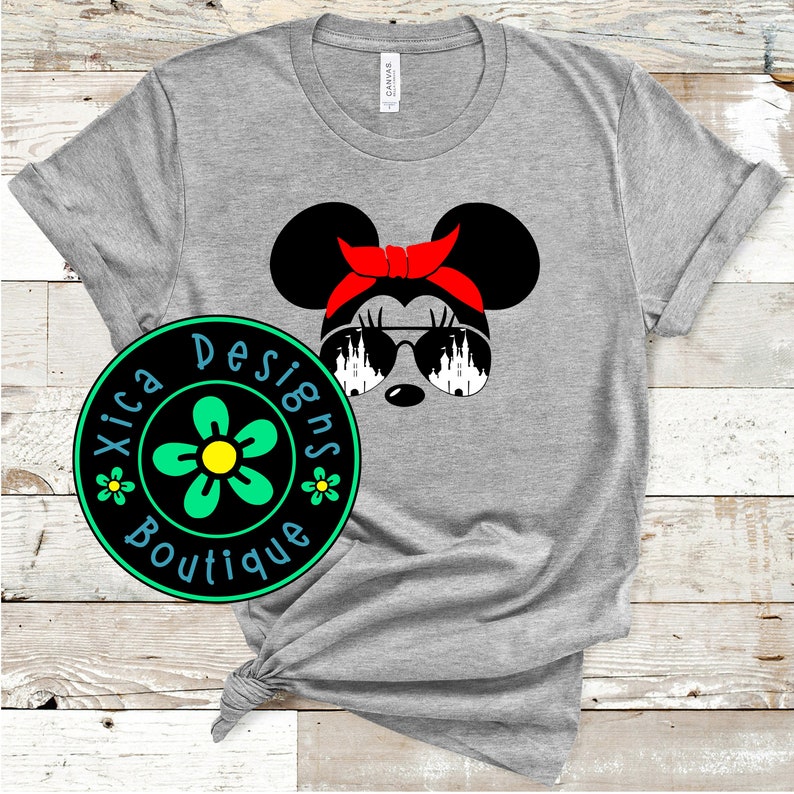 May include: Gray t-shirt with a black and white illustration of a cartoon mouse wearing red sunglasses and a red headband. The mouse is looking to the right. The text "Xica Designs Boutique" is on a green and yellow flower graphic.