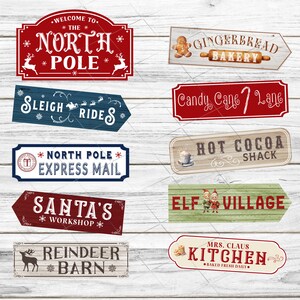 May include: Ten vintage-style wooden signs with Christmas themes. The signs feature red, blue, green, and brown colors. The signs have text that reads: "Welcome to the North Pole", "Sleigh Rides", "North Pole Express Mail", "Santa's Workshop", "Reindeer Barn", "Gingerbread Bakery", "Candy Cane Lane", "Hot Cocoa Shack", "Elf Village", and "Mrs. Claus Kitchen - Baked Fresh Daily".
