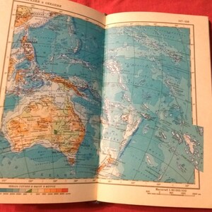 May include: A vintage map of Australia and surrounding islands, including New Guinea, Indonesia, and the Philippines. The map is printed in blue, green, yellow, and brown, with a scale of 1:80,000,000.