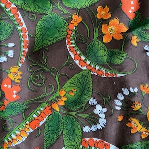 May include: A brown fabric with a repeating pattern of orange and white flowers, green leaves, and orange and white seed pods.