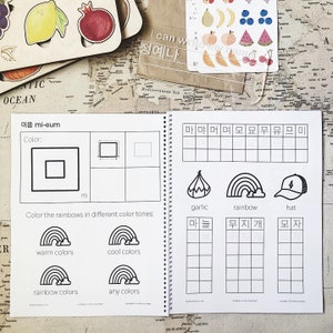 May include: A black and white workbook with Korean alphabet practice pages. The pages feature a variety of exercises, including tracing letters, writing words, and coloring pictures. The workbook is designed to help children learn the Korean alphabet.