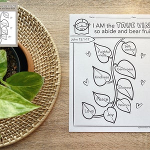 May include: Black and white printable coloring page featuring a vine with leaves and hearts. The vine represents the "True Vine" and each leaf has a fruit of the spirit written on it: love, joy, peace, patience, kindness, goodness, gentleness, faithfulness, and self-control. The text "I AM the TRUE VINE so abide and bear fruit" is at the top of the page. The scripture reference "John 15:1-17" is below the text.